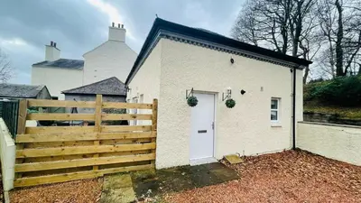 a white house with a white door and a fence at The Old Stables 17a in Dumfries