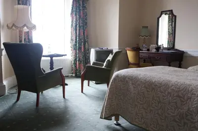 a bedroom with a bed and two chairs and a desk at North West Castle Hotel in Stranraer