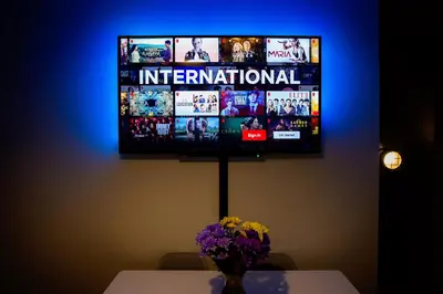 a tv hanging on a wall with a table and flowers at St Andrews Guest House in Irvine