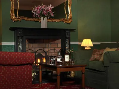 a living room with a fireplace with a couch and a table at Fernhill Hotel in Portpatrick