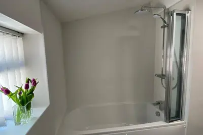 a bathroom with a shower and a vase of flowers at Poet's Corner - flat close to centre of Keswick in Keswick