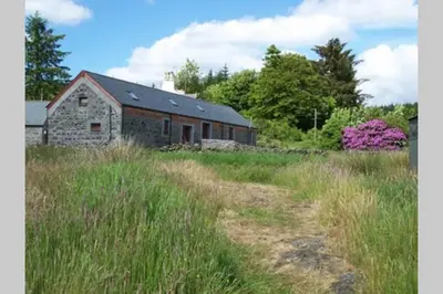 an old stone barn in a field of tall grass at Merrick Cottage in Bargrennan
