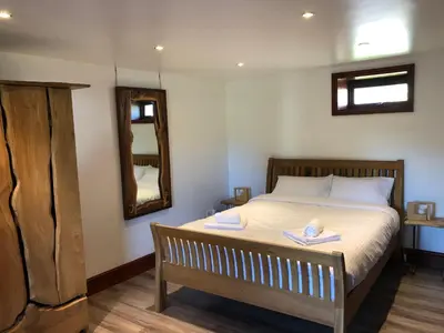 a bedroom with a bed with a mirror and a wooden bench at Anne's Cottage in Bargrennan