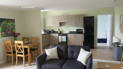 a living room with a couch and a kitchen at Dairy Cottage with sea views in Girvan