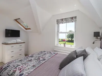 a bedroom with a bed with a dresser and a window at Seascape in Annan