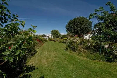 a path through a garden with flowers and trees at Troon Arts & Crafts Period Home Golf Beach in Troon