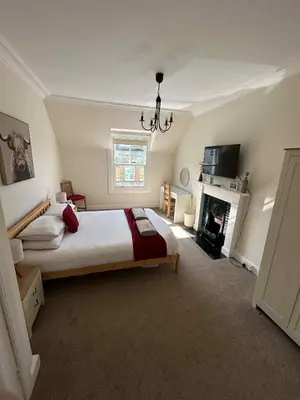 a bedroom with a large bed and a fireplace at 4 bedroom townhouse Kirkcudbright in Kirkcudbright
