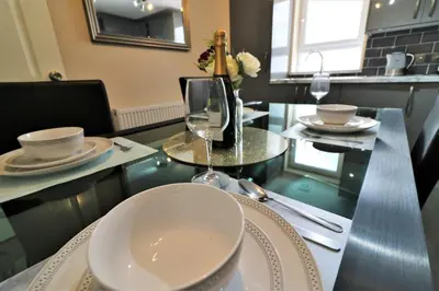 a dining table with glasses and a bottle of wine at Signature - Kirkhill Lower in Kirkmuirhill