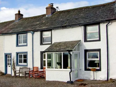 a white house with windows and chairs in front of it at 2 Mellfell View in Penrith
