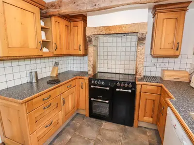 a kitchen with wooden cabinets and a black stove top oven at Two Town End in Penrith