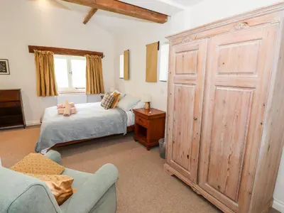 a bedroom with a bed and a large wooden closet at Two Town End in Penrith