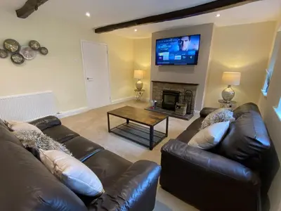a living room with a leather couch and a fireplace at Rattlebeck Farm Cottage and Hot Tub PET FRIENDLY in Welton