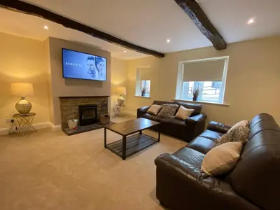 a living room with a leather couch and a fireplace at Rattlebeck Farm Cottage and Hot Tub PET FRIENDLY in Welton
