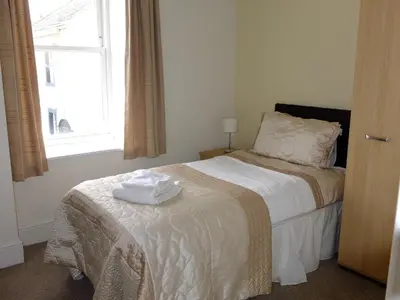 a bedroom with a bed with a white blanket and a window at The Golden Lion Hotel in Maryport