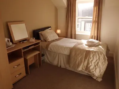 a bedroom with a bed and a desk with a mirror at The Golden Lion Hotel in Maryport