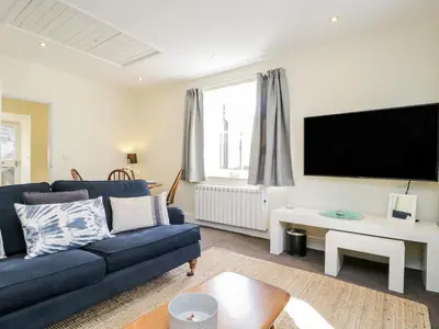 a living room with a blue couch and a flat screen tv at The Bakers Loft in Ambleside