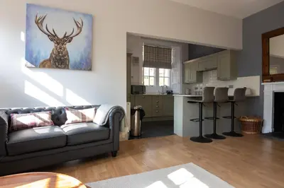 a living room with a couch and a kitchen at Laundry Cottage: Drumlanrig Castle in Thornhill