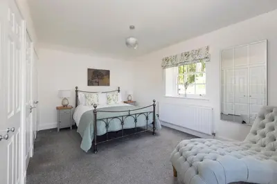 a bedroom with a bed and a chair and a window at Laundry Cottage: Drumlanrig Castle in Thornhill