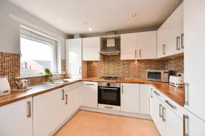 a kitchen with white cabinets and a window at Troon Executive Apartment in Troon