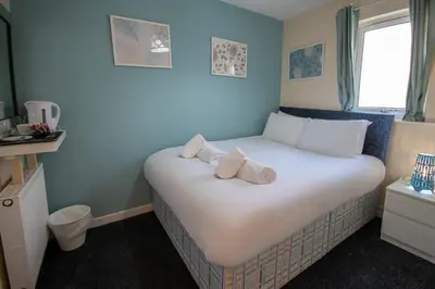 a bedroom with a white bed with towels on it at Irvine Riverside Guesthouse in Irvine