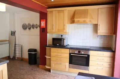 a kitchen with wooden cabinets and a microwave at Carvetii - Uriah House - 4-Bedroom House sleeps up to 10 people in Belle Vue