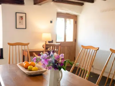 a vase with flowers and fruit on a wooden table at Wayside Cottage 1637 in Millom