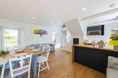 a kitchen and living room with a table and chairs at Nether Newton - Sleeps 12, Hottub, Sauna, Private Garden in Newmilns