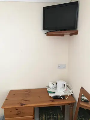 a wooden table with a tv on a wall at The Maxwell Arms Hotel in Dalbeattie