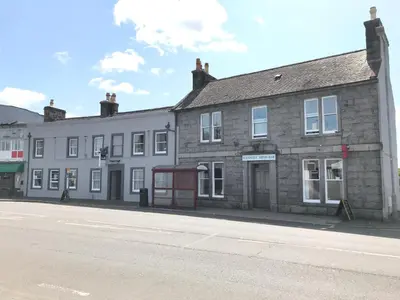 an old stone building on the side of a street at The Maxwell Arms Hotel in Dalbeattie