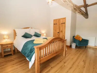 a bedroom with a bed and a wooden floor at Carrock Cottage in Dalston
