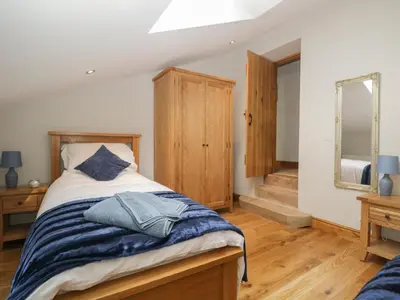 a bedroom with a bed with a wooden headboard and a mirror at Carrock Cottage in Dalston