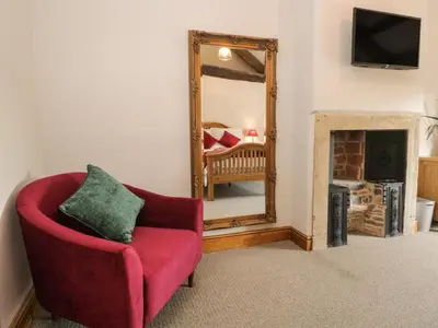 a living room with a red chair and a mirror at Carrock Cottage in Dalston
