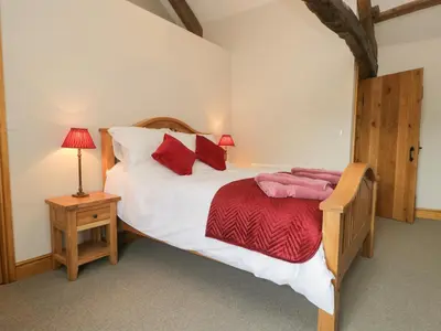a bedroom with a large bed with red pillows at Carrock Cottage in Dalston
