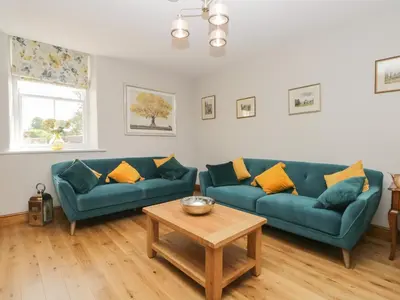 a living room with two blue couches and a table at Carrock Cottage in Dalston