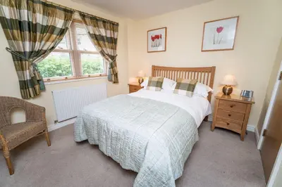 a bedroom with a bed and a chair and a window at 11 Howrah's Court in Keswick