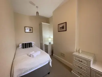 a small bedroom with a bed and a dresser at Abacourt Cottage in Keswick