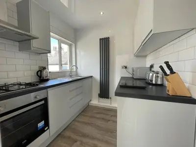 a kitchen with white appliances and a black counter top at Abacourt Cottage in Keswick