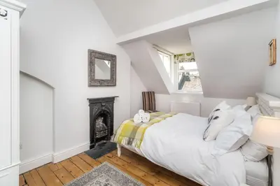 a white bedroom with a bed and a fireplace at 3 The Townhouse in Keswick