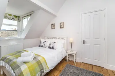 a white bedroom with a bed and a window at 3 The Townhouse in Keswick