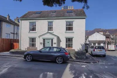 a blue car parked in front of a white house at Acorn Cottage in Keswick