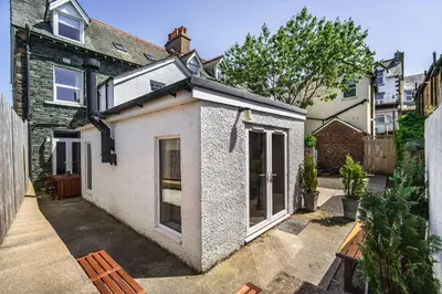 a small white house with a bench in a courtyard at 9 The Townhouse in Keswick