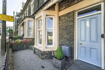 a brick house with a blue door and a potted plant at 7 The Townhouse in Keswick