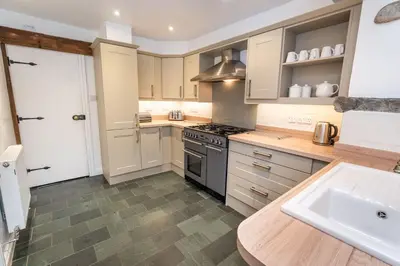 a kitchen with white cabinets and a stove top oven at Barf Cottage in Portinscale