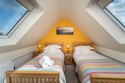 two beds in a attic room with windows at Skiddaw Skies in Keswick