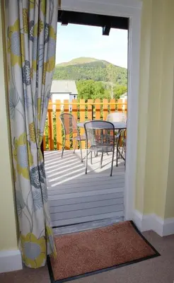 a door leading to a deck with a table and chairs at Skiddaw Skies in Keswick