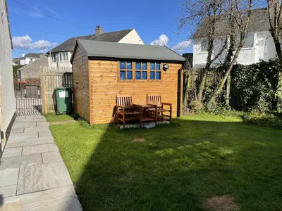 a wooden shed with two chairs and a table in a yard at Appletree in Portinscale