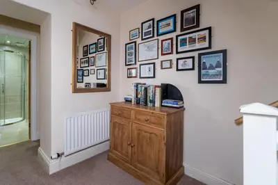 a room with a tv on a wall with pictures at The Ridgeway in Keswick