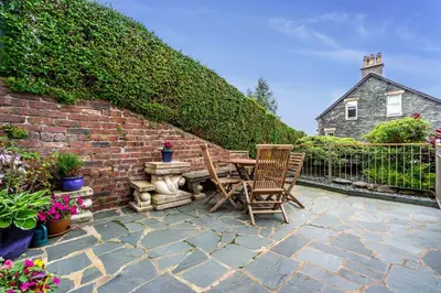 a patio with a table and chairs and a brick wall at The Ridgeway in Keswick