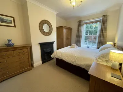a bedroom with a bed and a fireplace and a mirror at Tawny Cottage in Portinscale