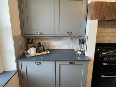 a kitchen with white cabinets and a blue counter top at Tawny Cottage in Portinscale